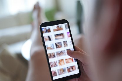 Un joven mira un sitio web pornográfico en un teléfono inteligente (escena escenificada).