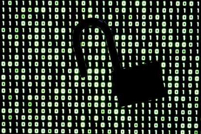Un candado frente a un código binario en la pantalla de una computadora portátil