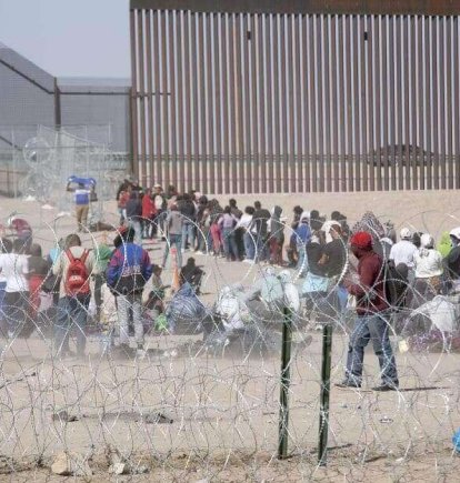 Migrantes en fila intentando cruzar la frontera entre Estados Unidos y México.