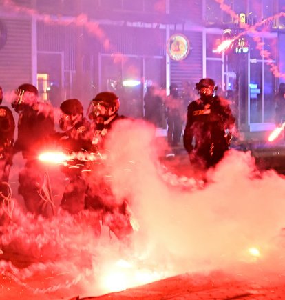 Fuegos artificiales explotan alrededor de agentes de policía con equipo antidisturbios durante una protesta en respuesta a las operaciones federales de inmigración en el barrio de Little Tokyo, en el centro de Los Ángeles, el 9 de junio de 2025. La administración del presidente Donald Trump dijo el 9 de junio que enviaba 700 marines estadounidenses y miles de efectivos más de la Guardia Nacional a Los Ángeles, lo que provocó una furiosa respuesta del gobernador de California por el 