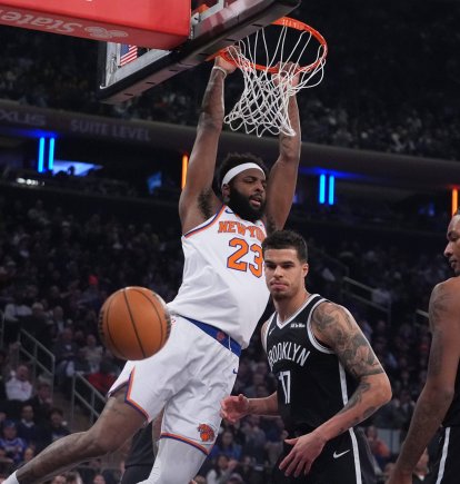 Mitchell Robinson (23), de los New York Knicks, clava el balón frente a Michael Porter Jr. (17) y Noah Clowney (21), de los Brooklyn Nets, durante la primera mitad de un partido de baloncesto de la NBA el miércoles 21 de enero de 2026 en Nueva York.