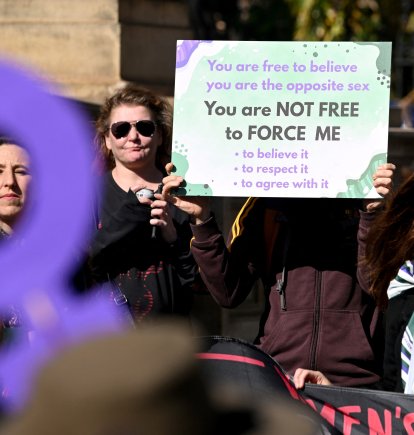 Personas sostienen pancartas y banderas en una manifestación de Women Will Speak en Melbourne el 16 de agosto de 2025, lamentando la erosión de los derechos de las mujeres ante las reivindicaciones de identidad transgénero.
