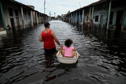 People walk through a flooded street in Batabano on September 26, 2024, after the passage of Hurricane Helene.