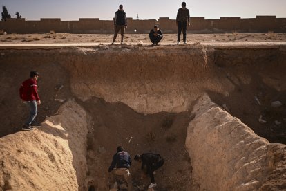 A group of people search for human remains in a suspected mass grave near Damascus