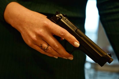 Una mujer con un arma en sus manos antes de guardarla en un área segura