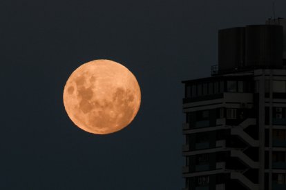 The moon rises in its crescent gibbous phase next to a building in Buenos Aires.