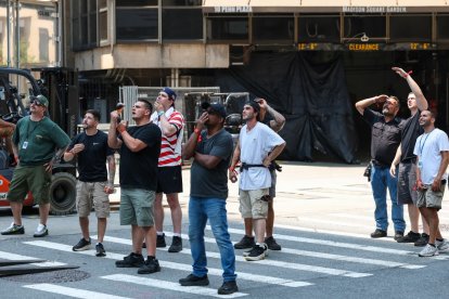 Workers near Madison Square Garden stop and look toward the Empire State Building