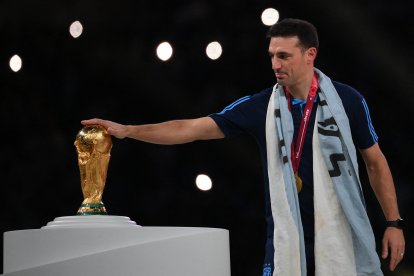 Argentina's coach Lionel Scaloni touches the World Cup trophy.
