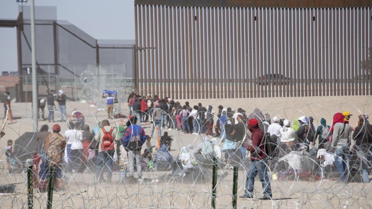 Migrantes en fila intentando cruzar la frontera entre Estados Unidos y México.