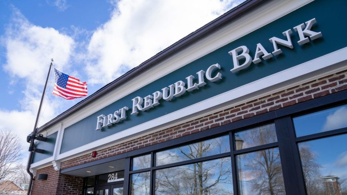 Sede del banco First Republic Bank vista desde afuera. Hay un cartel con el nombre del banco escrito en letras blancas sobre fondo verde. También puede verse una bandera norteamericana.