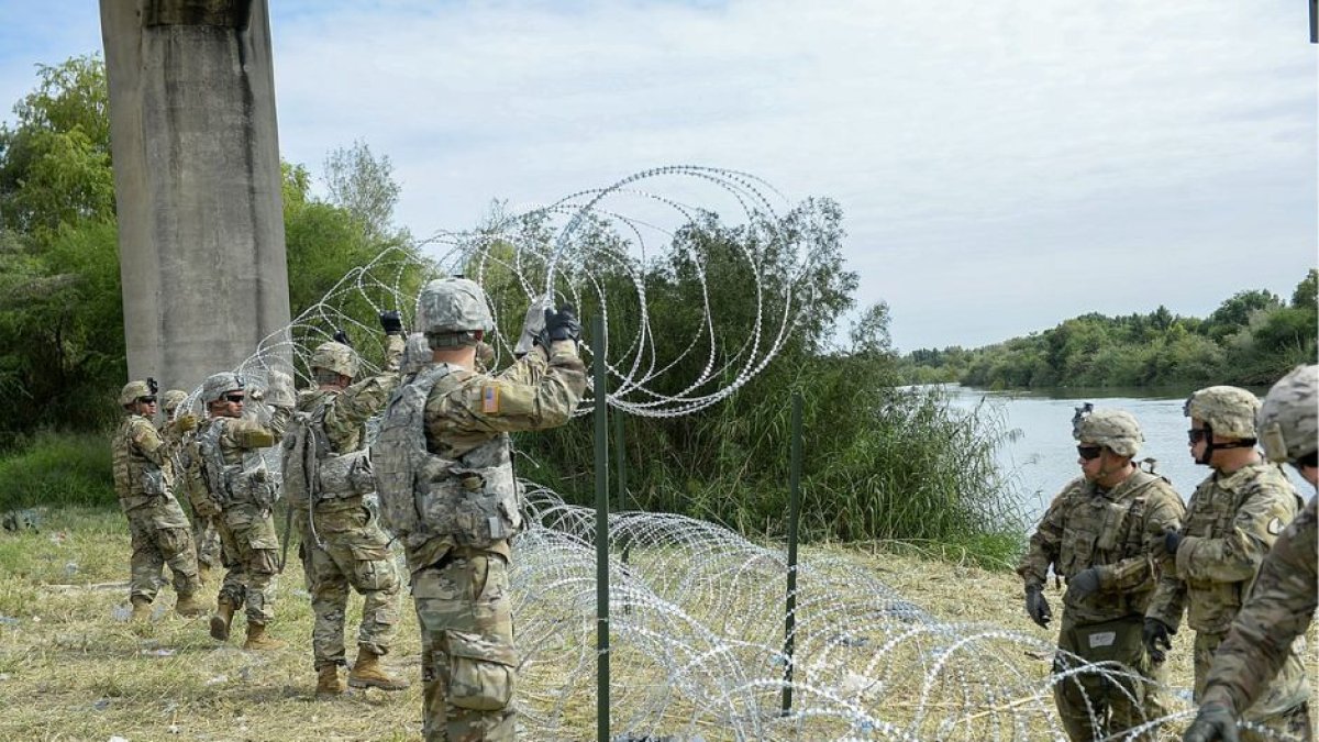 Militares de la Guardia Nacional en la frontera con México levantan una alambrada.