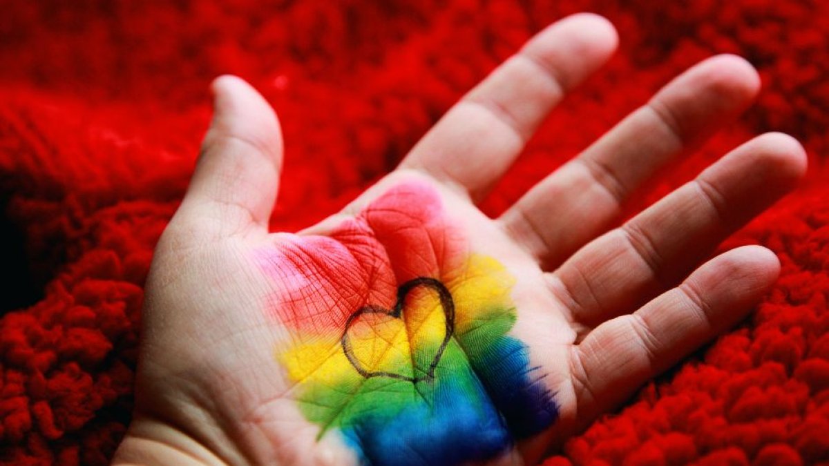 Mano de un niño pintada con los colores de la bandera LGBT y un corazón.