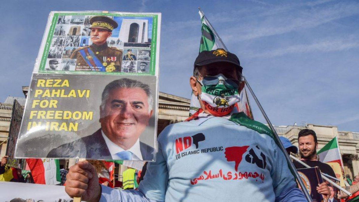 Un manifestante lleva un cartel de apoyo a Reza Pahlavi con su fotografía.