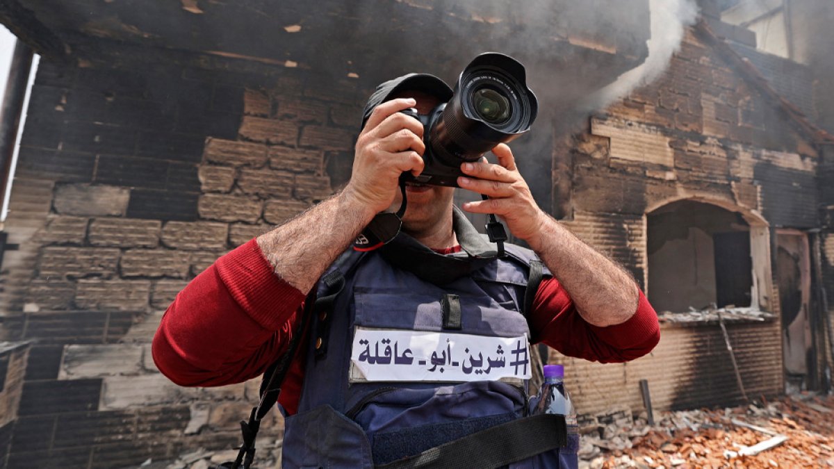 A reporter wearing a flak jacket with the hashtag in Arabic, 