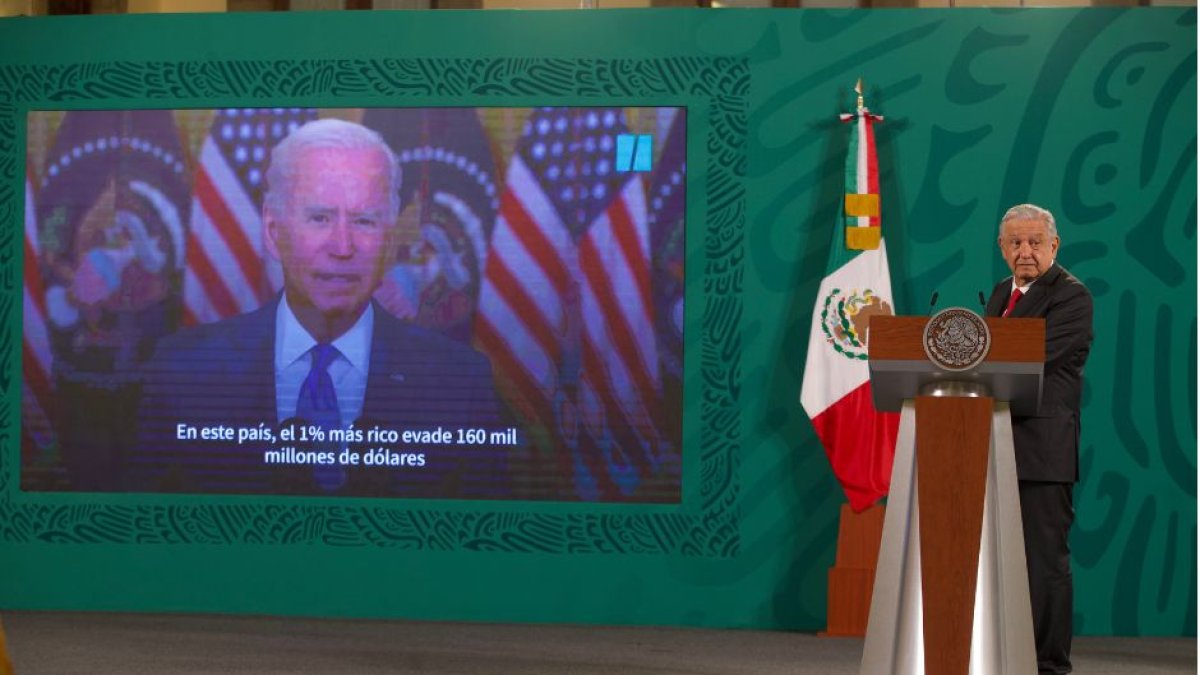 El presidente de México habla con una imagen de Joe Biden de fondo.