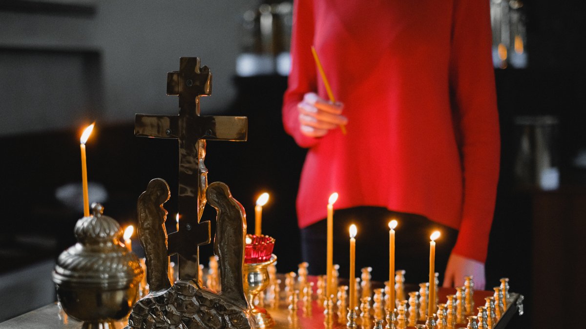 Torzo de mujer que encendiendo velas dentro de una iglesia.