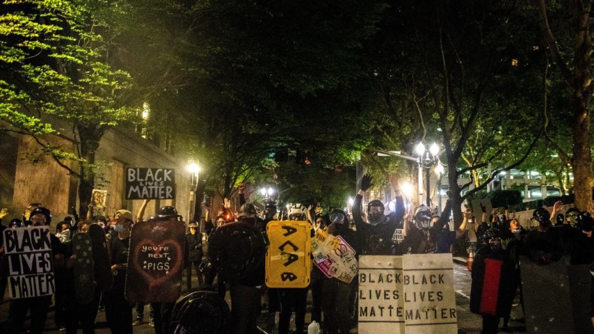 Alborotadores del Black Lives Matter portando pancartas contra la policía durante una manifestación.