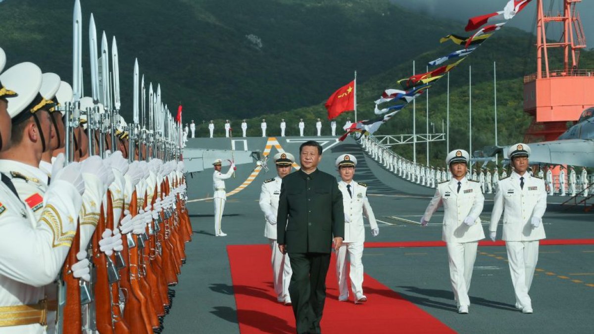 Xi Jinping camina al lado de miembros de las fuerzas armadas antes de abordar el portaviones Shandong.