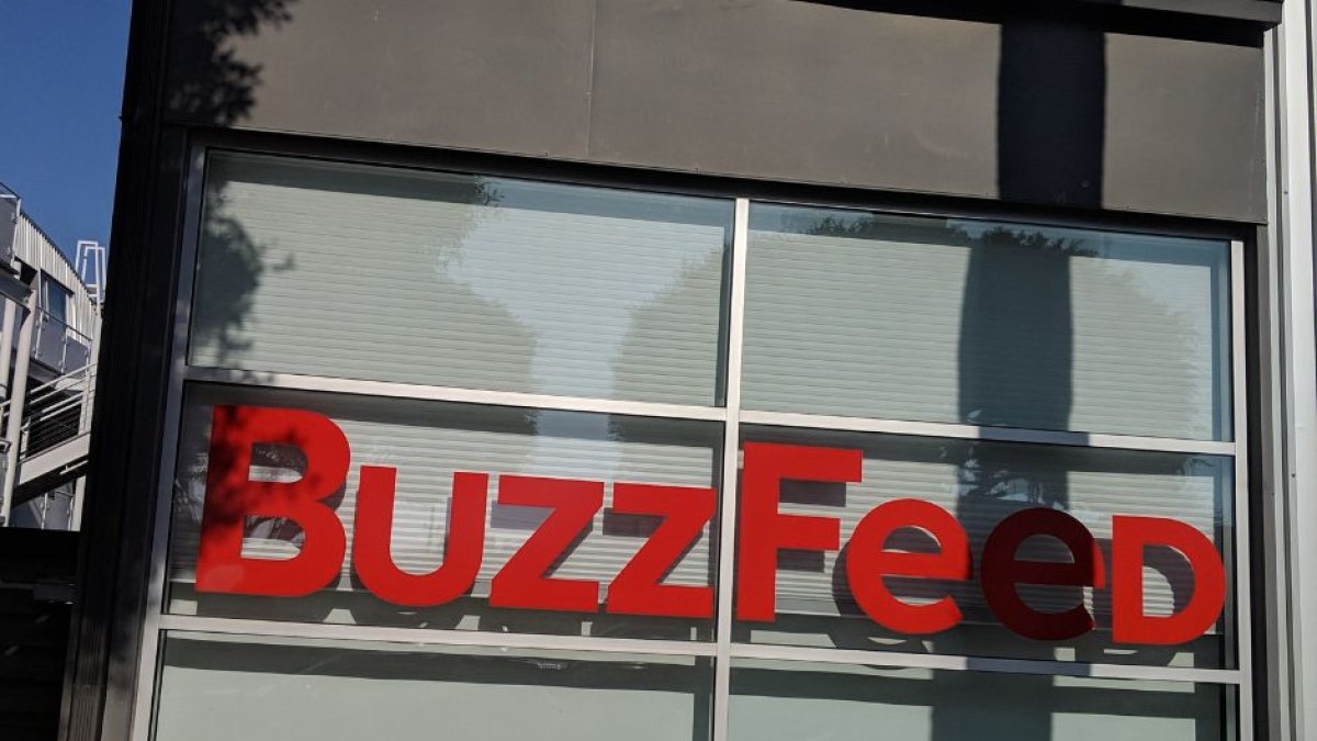 Foto de una oficina de BuzzFeed desde afuera donde se ven el nombre de la empresa en rojo contra la ventana.