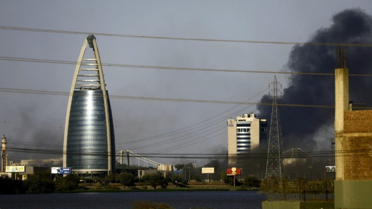 La imagen muestra la ciudad de Khartoum, capital de Sudán. Cerca de un edificio moderno, una columna de humo se eleva.