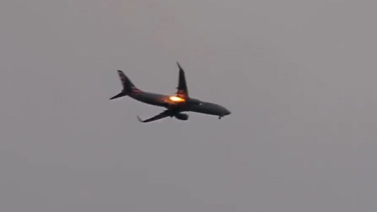 Se puede ver como el avión vuela en un cielo gris y una llamarada se desprende de su turbina.