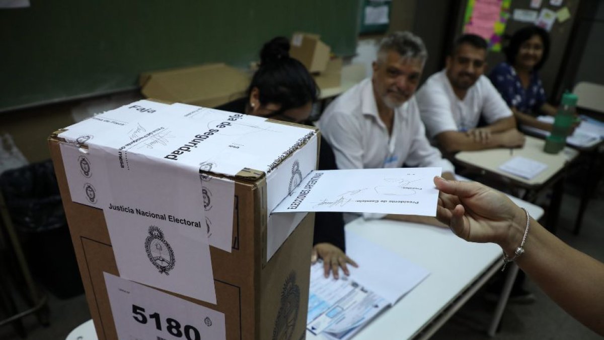 Imagen un votante introduciendo un voto dentro de una urna en el balotaje argentino.