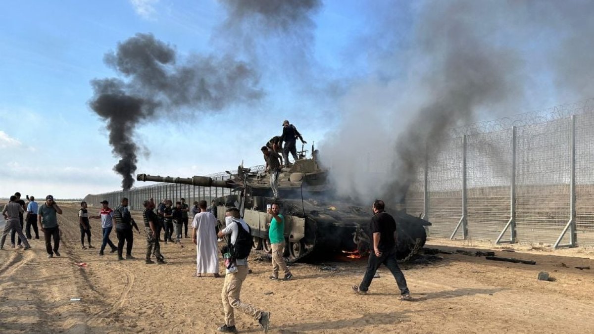 Imagen de archivo de terroristas de Hamás quemando un vehículo militar israelí en la frontera de Israel con Gaza.