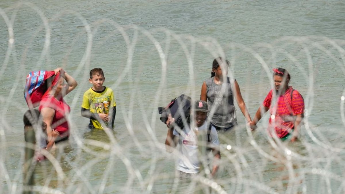A group of migrants look for an opening in the concertina wire barrier south of Eagle Pass