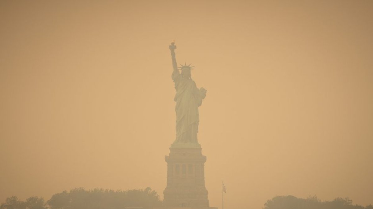 Imagen de la Estatua de la Libertad, en Nueva York, teñida de naranja a consecuencia de la nube tóxica proveniente de Canadá.