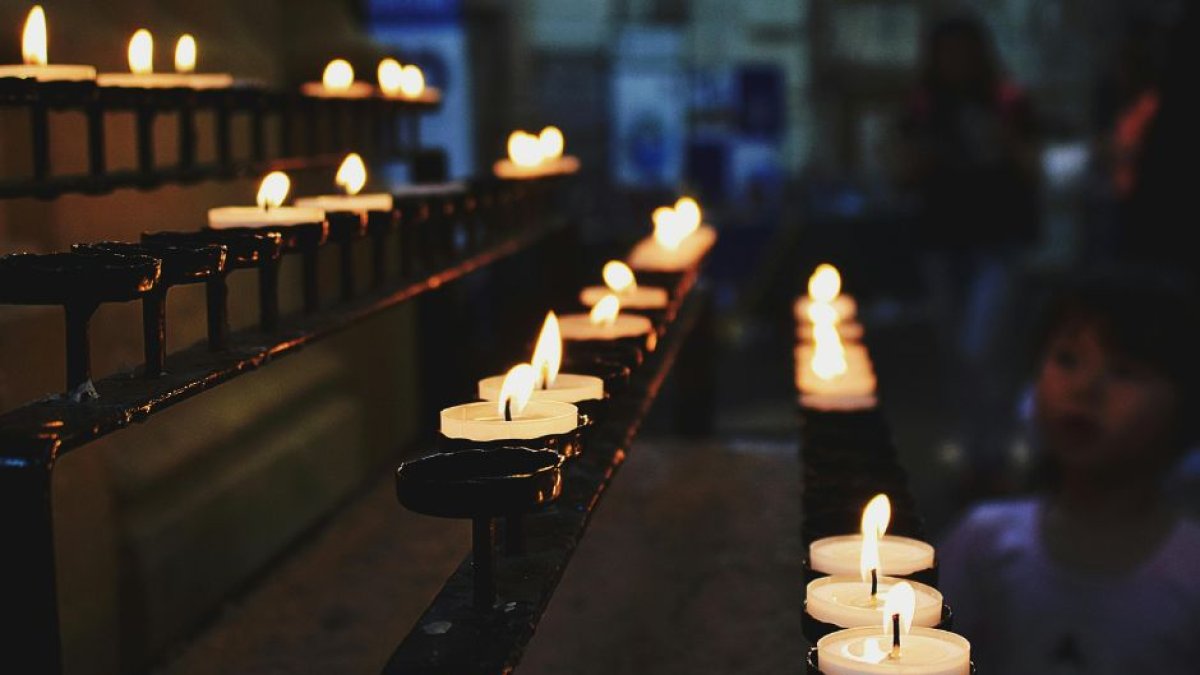 Imagen de archivo de unas velas de plegaria encendidas dentro de una iglesia.