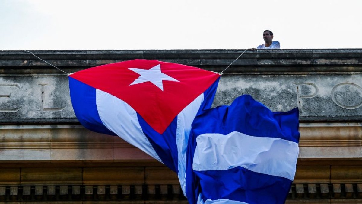 Un hombre ata una bandera cubana en el techo de la Universidad de La Habana
