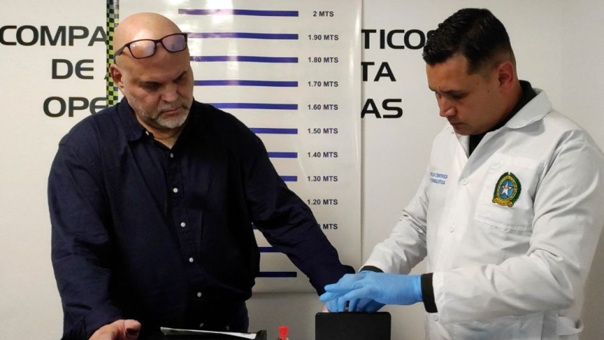 A picture released by the Colombian Interpol shows Colombian-Italian former paramilitary chief Salvatore Mancuso (L) with a member of the forensic police upon his arrival at the El Dorado International Airport in Bogota