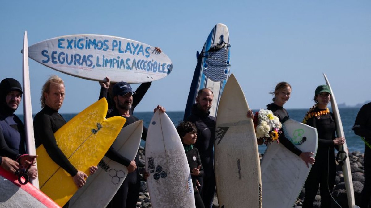 Surfistas de pie antes de participar en una ceremonia en honor de dos australianos y un surfista estadounidense que desaparecieron la semana pasada durante un viaje de surf en la playa de San Miguel en Ensenada, estado de Baja California, México, el 5 de mayo de 2024.