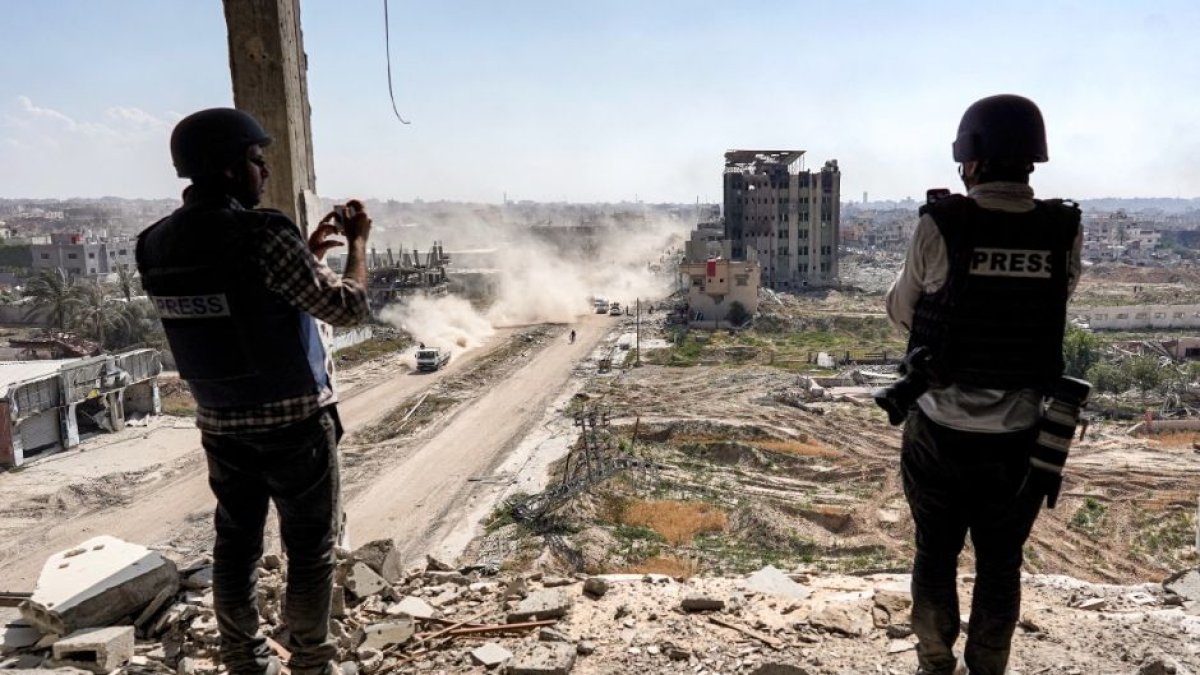 Periodistas filman desde lo alto de un edificio dañado frente al devastado edificio del hospital Al-Salam en Khan Yunis el 7 de abril de 2024