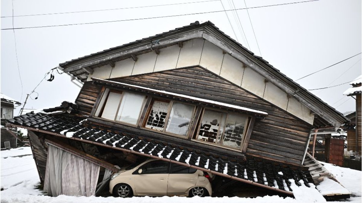Un coche dañado yace bajo un edificio derrumbado en la ciudad de Shika, en el distrito de Hakui, prefectura de Ishikawa, el 8 de enero de 2024.