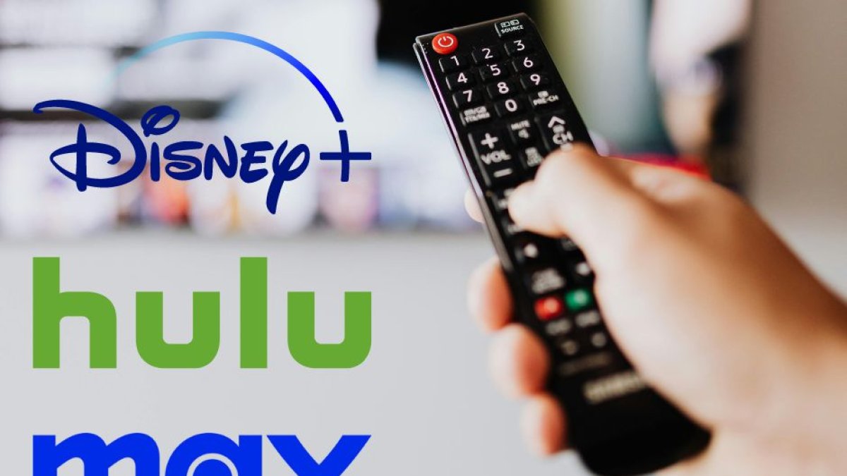 A la derecha: una mano sosteniendo un mando a distancia. A la izquierda, los logos de Disney+, Hulu y Max. Las tres plataformas se unirán para crear un único servicio en streaming.