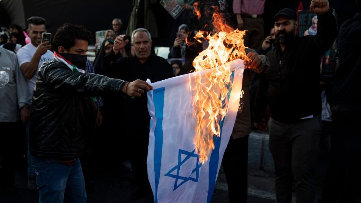 Manifestantes pro Palestina queman una bandera de Israel.