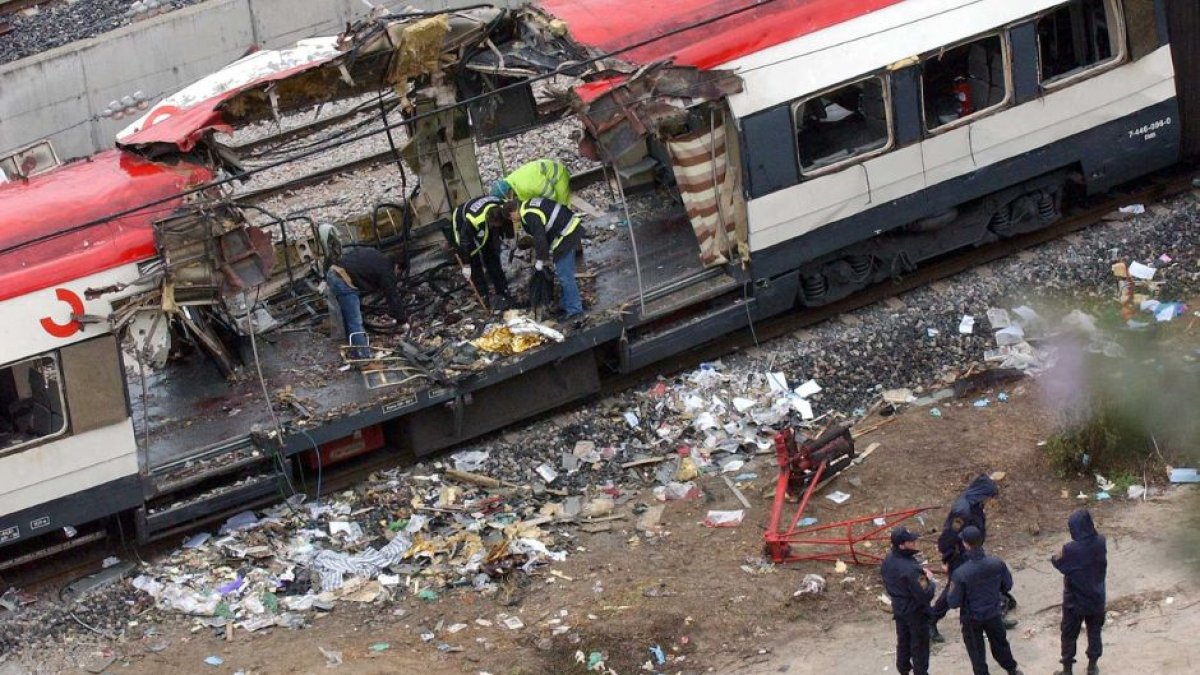 Trabajadores ferroviarios españoles y expertos forenses buscan restos mortales y examinan los escombros de los trenes destruidos en la estación de Atocha de Madrid el viernes 12 de marzo de 2004.