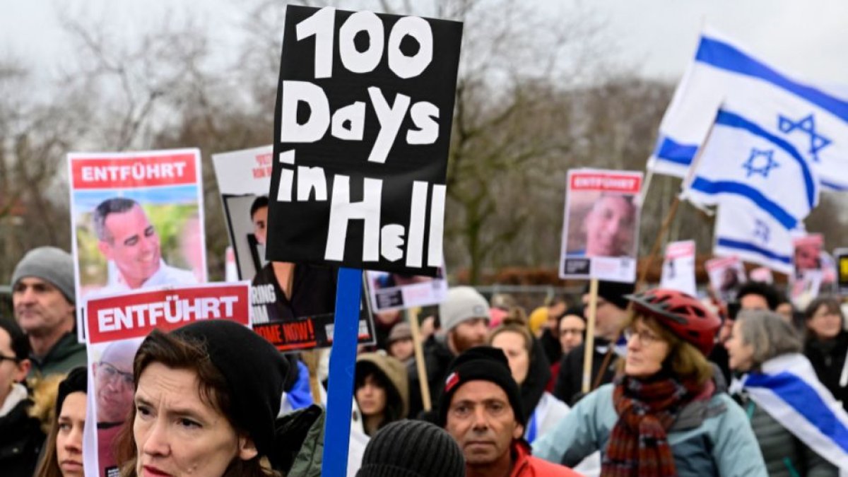 Demonstrators carry Israeli flags and placards with the portraits of Israeli hostages during a march to mark the 100th day of the Israeli hostages' captivity during the ongoing Israeli-Palestinian conflict, on January 14, 2024 in Berlin.