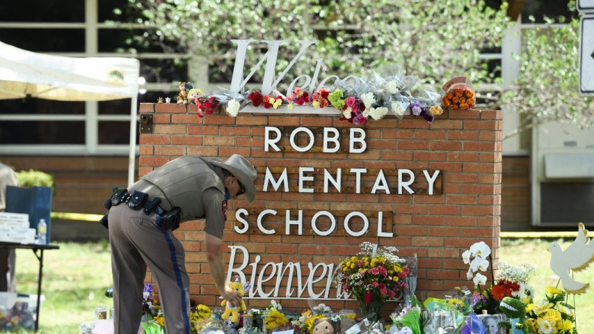 Un agente de policía de Uvalde deposita fotos en la escuela en la que se produjo la masacre.