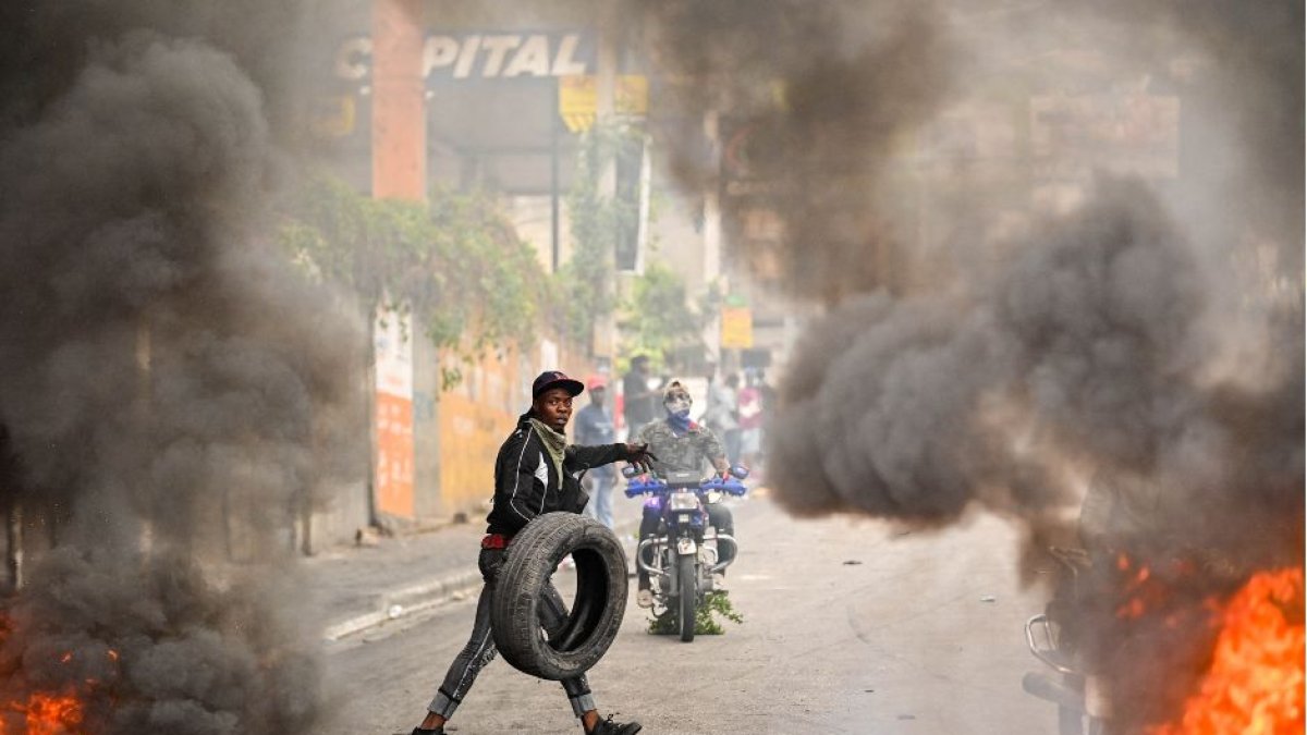 Un manifestante quema neumáticos durante una manifestación que pedía la dimisión del primer ministro Ariel Henry en Puerto Príncipe el 7 de febrero de 2024. / AFP