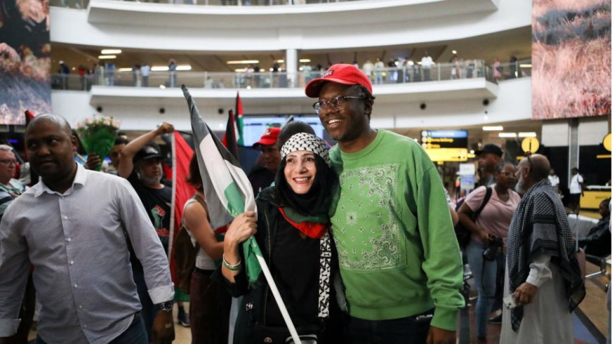 El abogado Tembeka Ngcukaitobi (d), miembro del equipo jurídico sudafricano, es saludado por un simpatizante, tras aterrizar de vuelta en el país después de representar al país en una audiencia de dos días contra Israel en la Corte Internacional de Justicia (CIJ), en el Aeropuerto Internacional OR Tambo en Ekurhuleni, Sudáfrica, el 14 de enero de 2024.