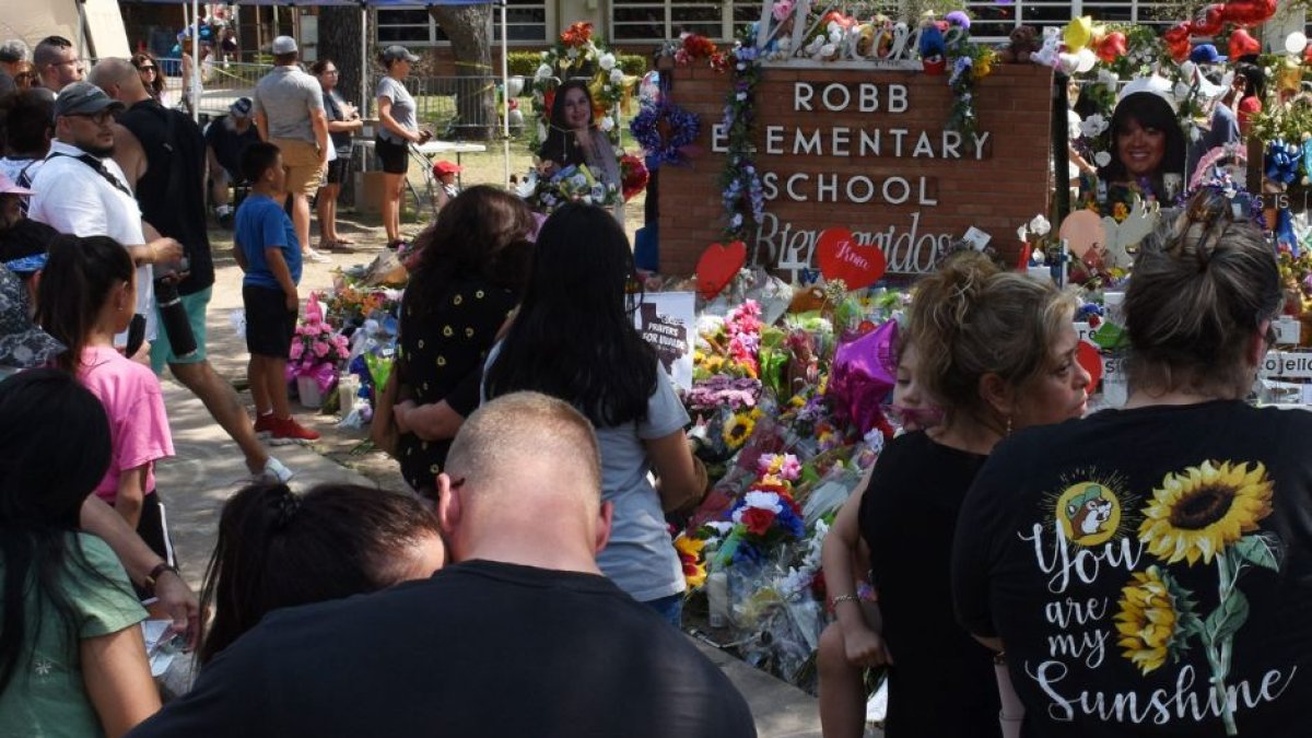 Los dolientes se reúnen en un monumento de flores en la Escuela Primaria Robb en Uvalde, Texas, el lunes 30 de mayo de 2022. Un tiroteo masivo días antes dejó 19 niños y dos adultos muertos en la escuela primaria.