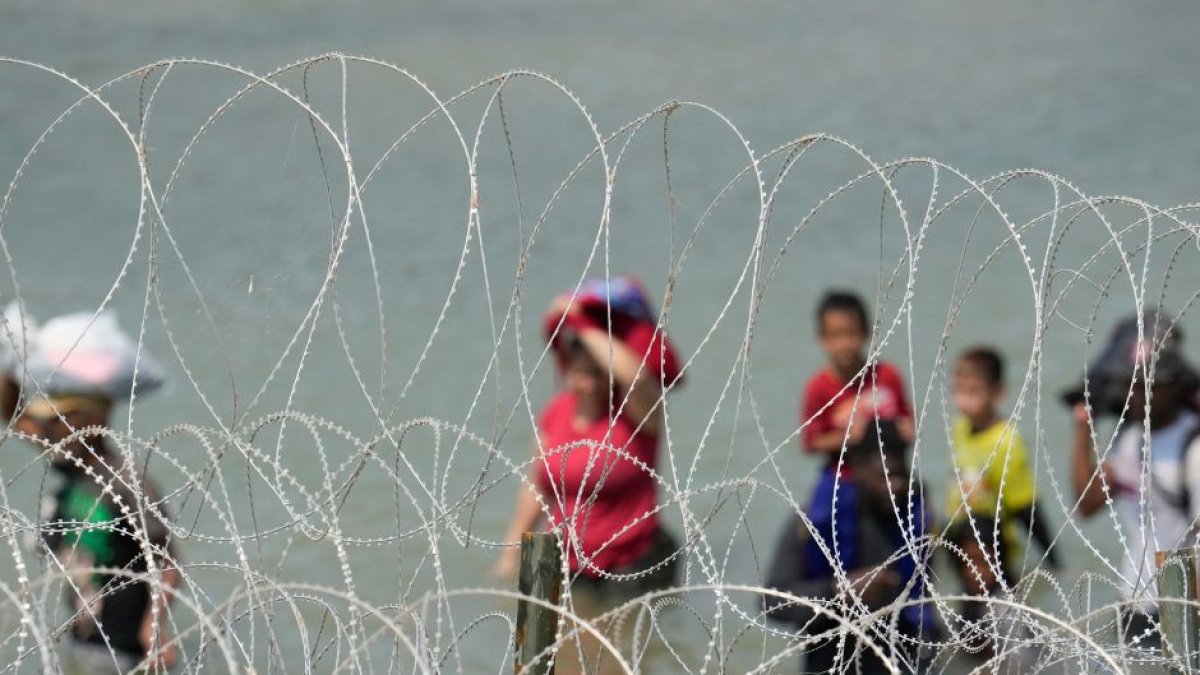Un grupo de migrantes busca una abertura en la barrera de alambre concertina | Cordon Press