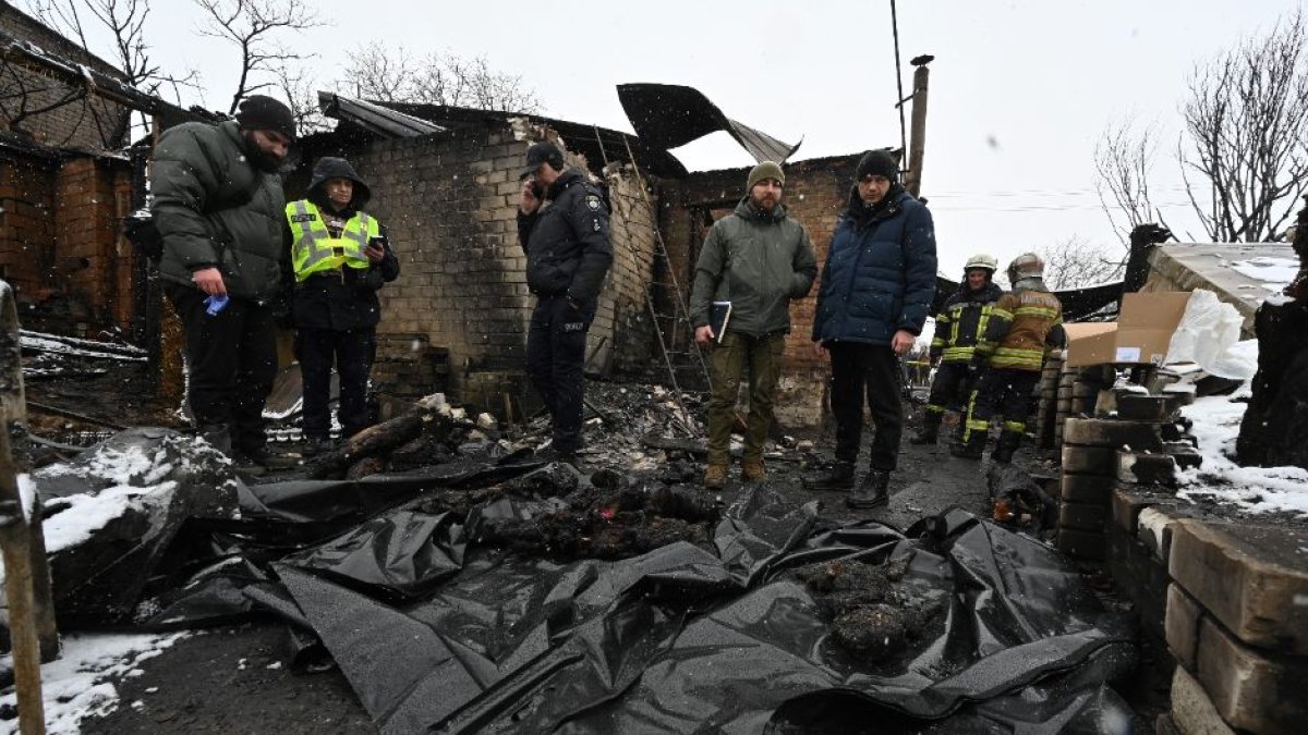 Algunos policías se paran frente a cuerpos cubiertos con bolsas de plástico en el lugar de un ataque con drones en Kharkiv