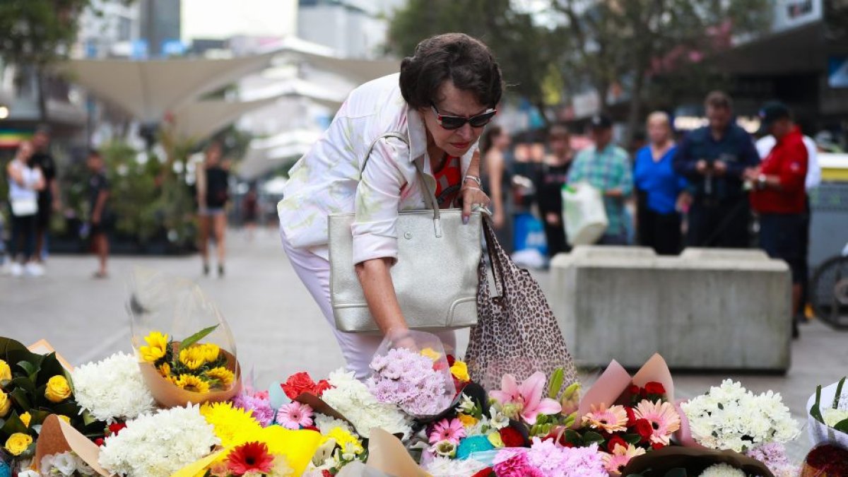 Una mujer deposita flores frente al centro comercial Westfield en Bondi Junction, en Sídney, Australia, el 14 de abril de 2024.