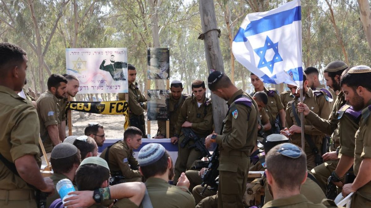 Soldados israelíes visitan un monumento conmemorativo con los retratos de las personas cautivas o muertas en el ataque de Hamás contra el festival de música Supernova el 7 de octubre, en el lugar donde se celebró el festival, cerca del kibutz Reim, en el sur de Israel, el 7 de abril de 2024.