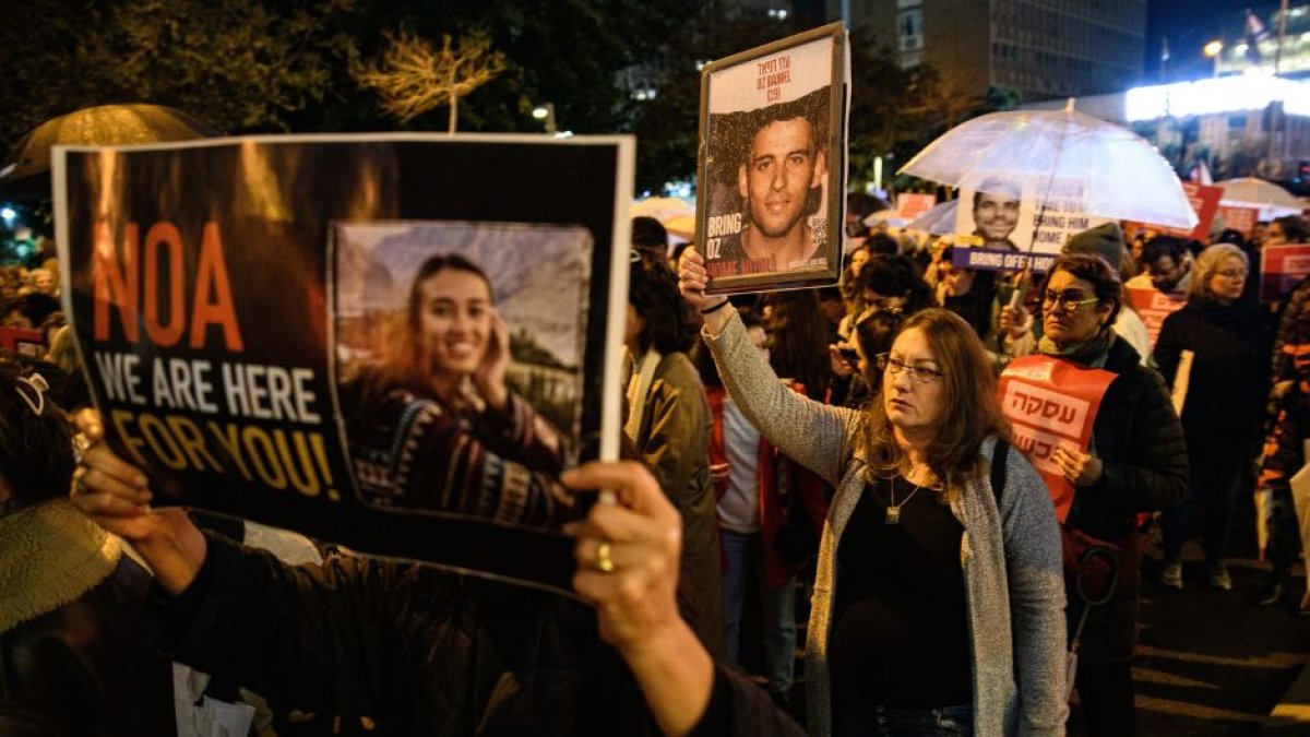 Mujeres israelíes marchan mientras sostienen carteles con las fotos de los rehenes israelíes Noa Argamani y Oz Daniel durante una manifestación en Tel Aviv en demanda de un acuerdo inmediato sobre los rehenes y un alto el fuego.