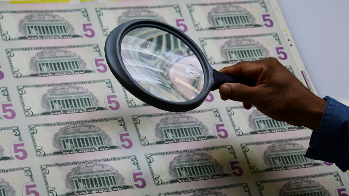 Un empleado examina una hoja de billetes de 5 dólares al salir de la máquina de impresión en la Oficina de Grabado e Impresión del Tesoro de EE.UU. en Washington.