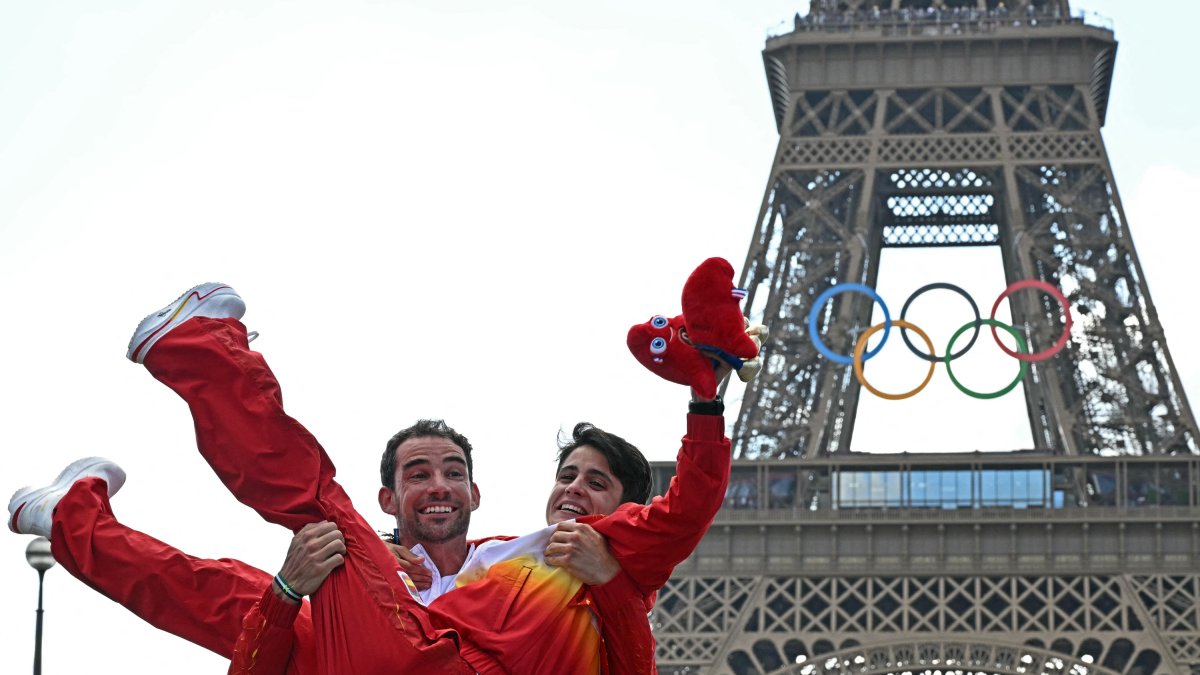 El marchador español Álvaro Martín coge en brazos a María Pérez para celebrar el oro en el maratón por relevos mixtos de marcha en el podio.